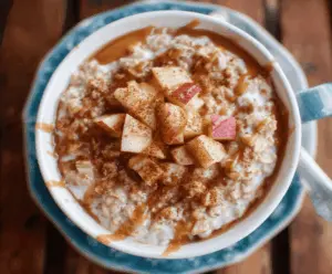 Creamy apple cinnamon oatmeal porridge topped with sliced apples, cinnamon, and a drizzle of honey in a rustic bowl