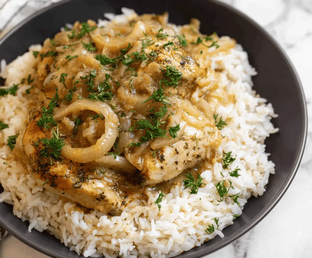 Delicious smothered chicken served over fluffy rice with gravy and fresh herbs, perfect for a comforting meal