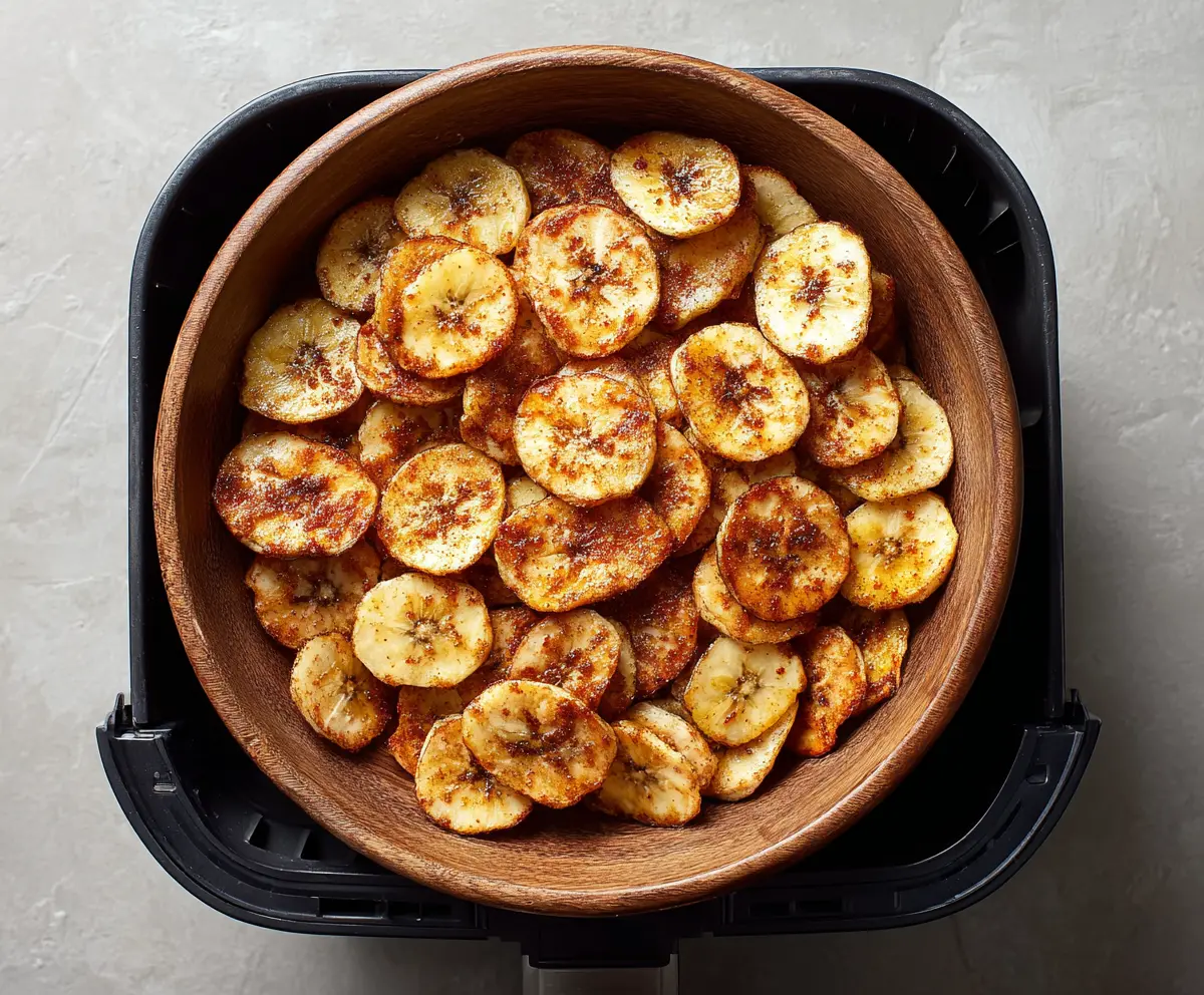 Crispy homemade air fryer cinnamon banana chips served on a plate with a sprinkle of cinnamon.