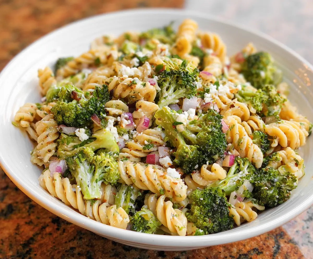 Fresh broccoli pasta salad with cherry tomatoes and herbs in a bowl, perfect for a healthy meal.