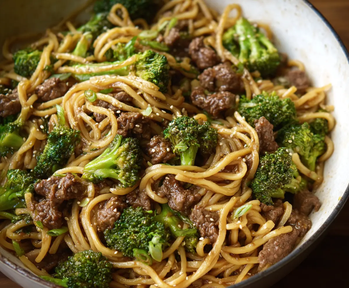 Delicious Garlic Ginger Beef and Broccoli Noodles in a white bowl, featuring tender beef, fresh broccoli, and flavorful noodles.