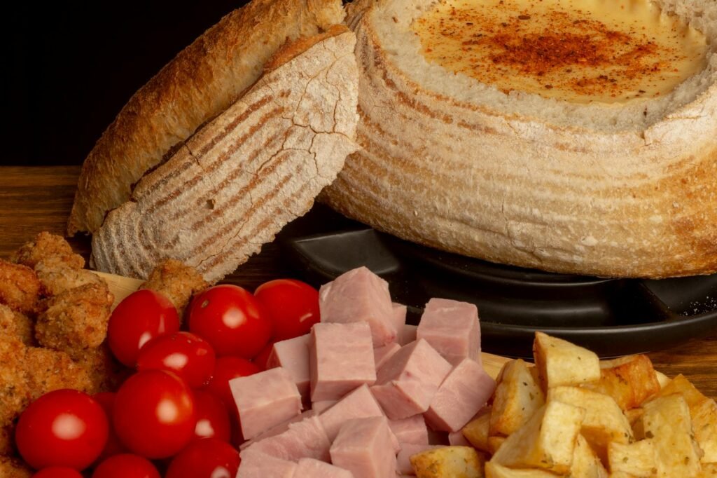 A pot of hearty soup on a dining table with sliced bread and simple toppings.