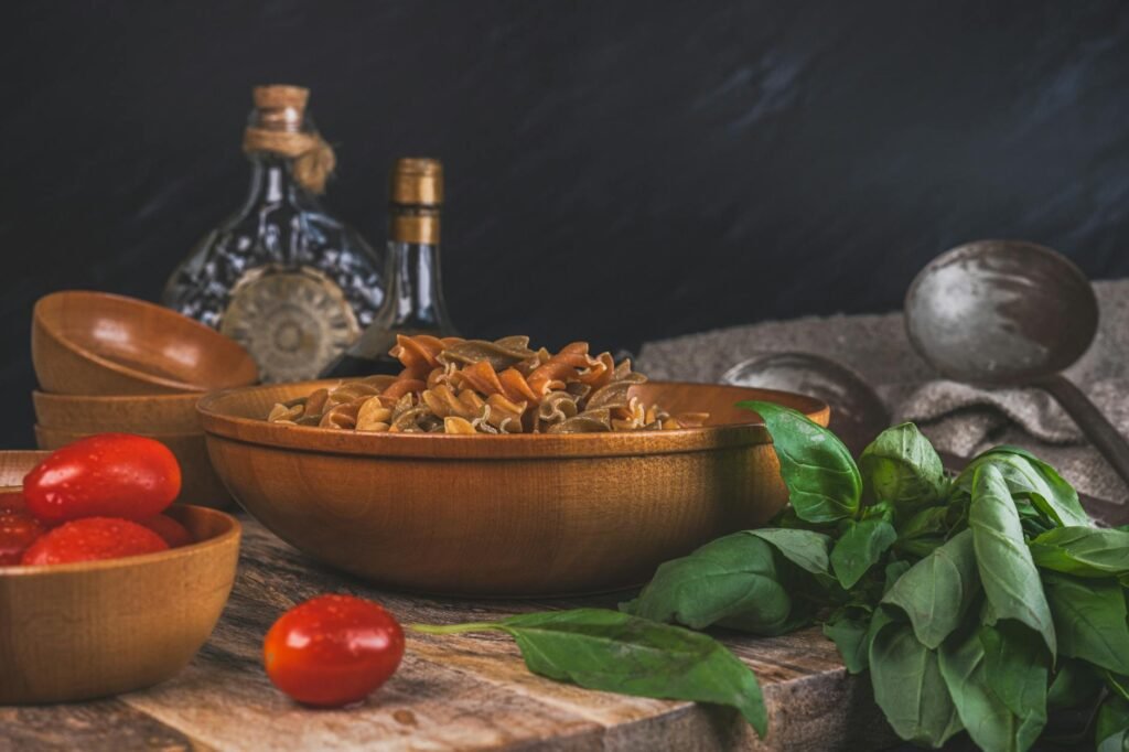 A skillet of pasta being tossed with tomato sauce on a home stove with grated cheese nearby