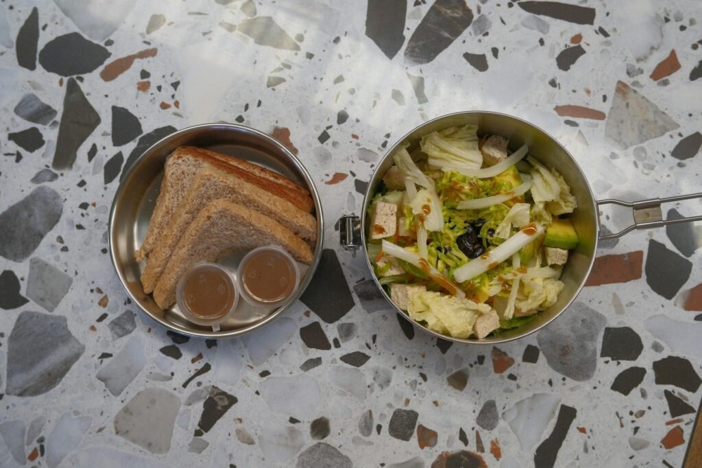Lunch components arranged separately on a kitchen counter with small sauce cups and containers