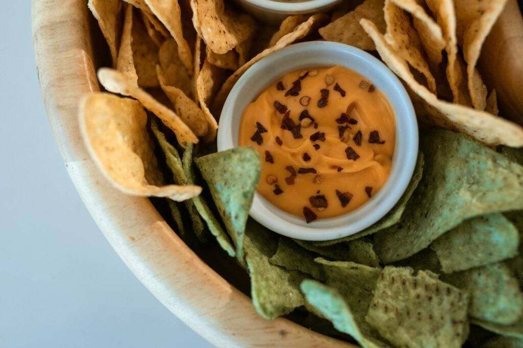 A slow cooker of queso next to a bowl of chips on a party table.