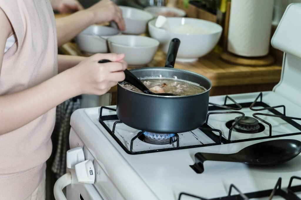 A pot of soup on the stove with a ladle lifting broth for a taste test