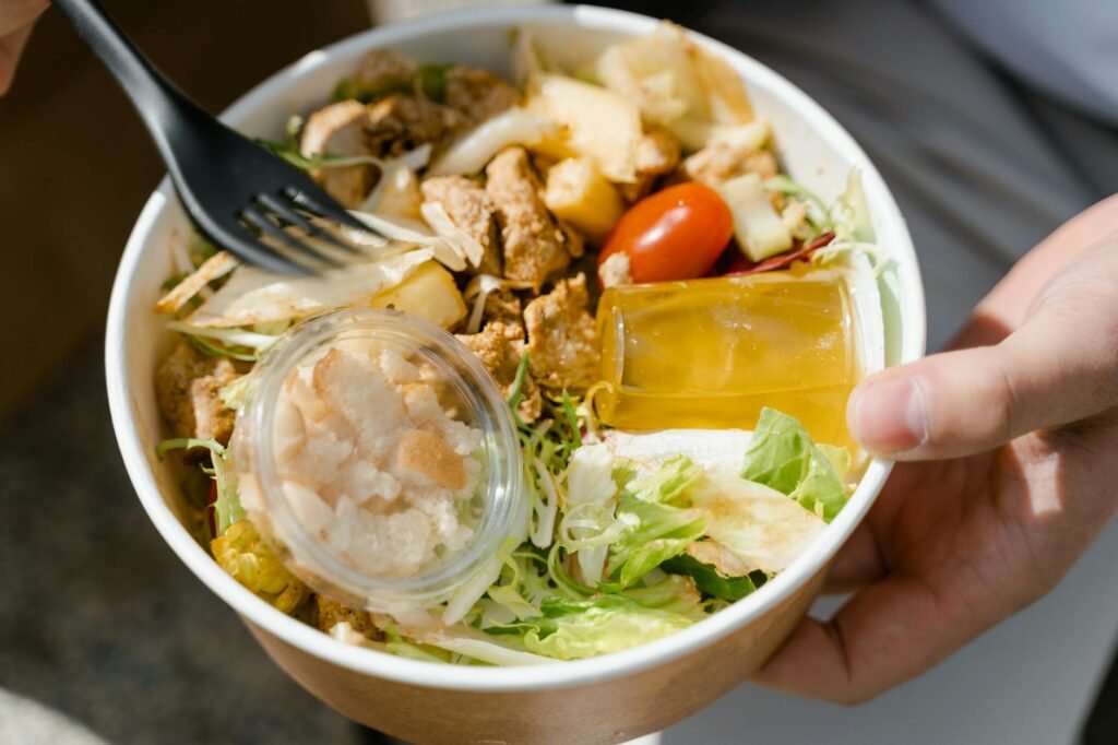 A packed salad with dressing and crunchy toppings kept in separate containers