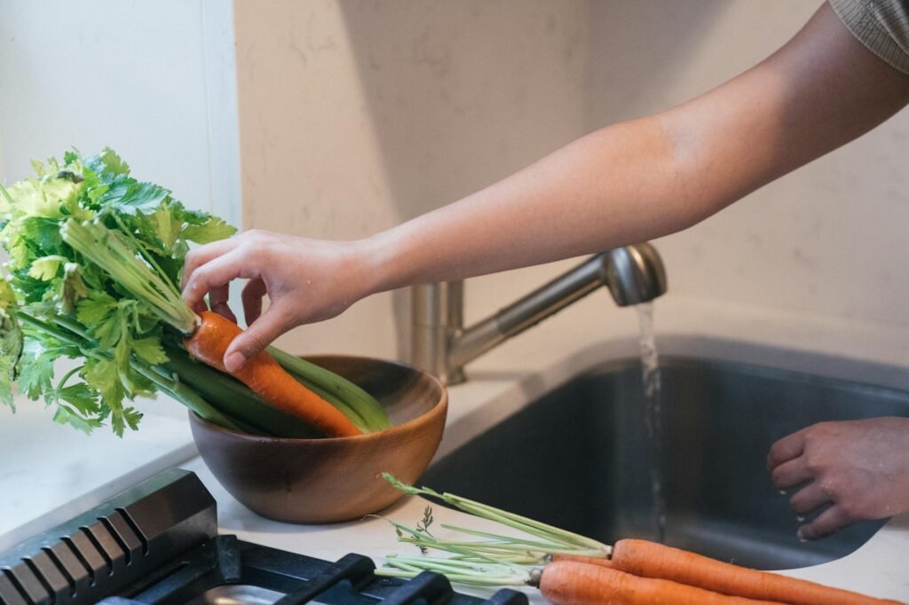 Freshly washed broccoli and carrots being dried with a kitchen towel on a counter