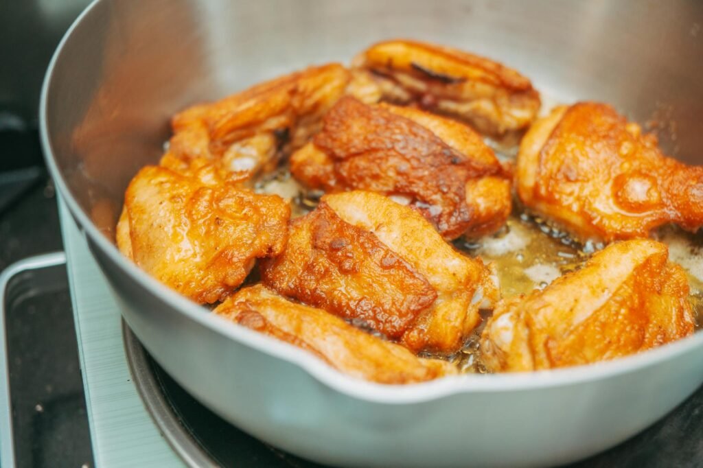 Chicken and onions browning in a skillet on a stovetop