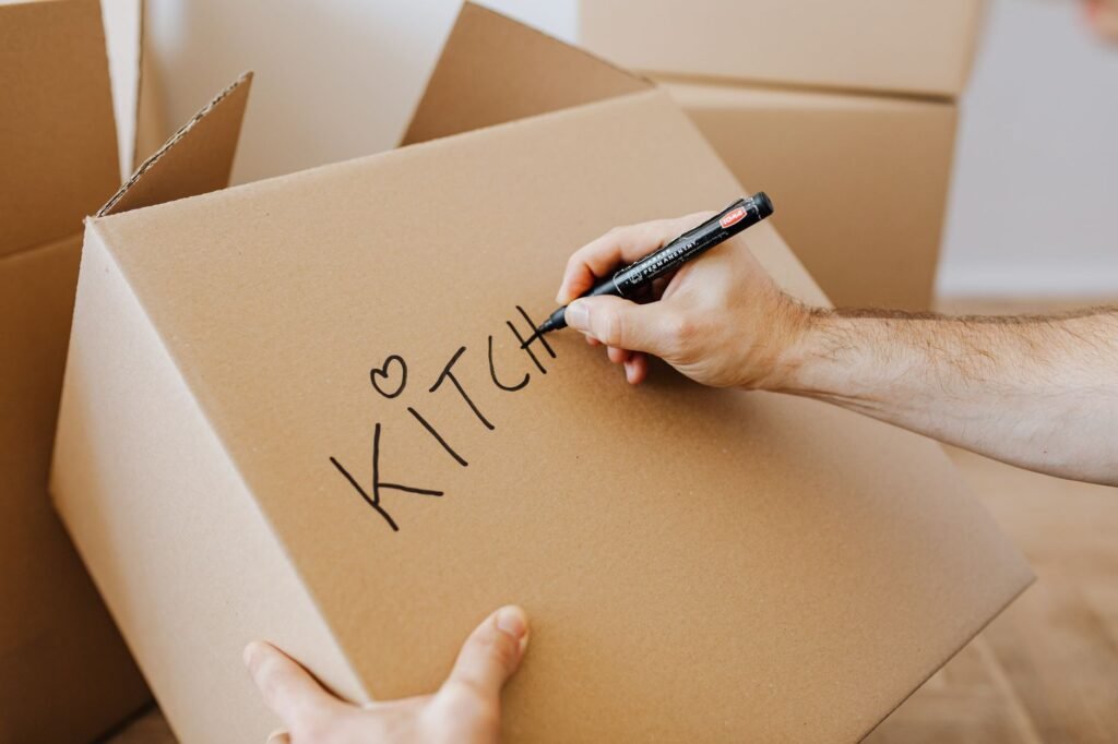 Containers, freezer bags, tape, and a marker arranged on a kitchen counter for labeling frozen food