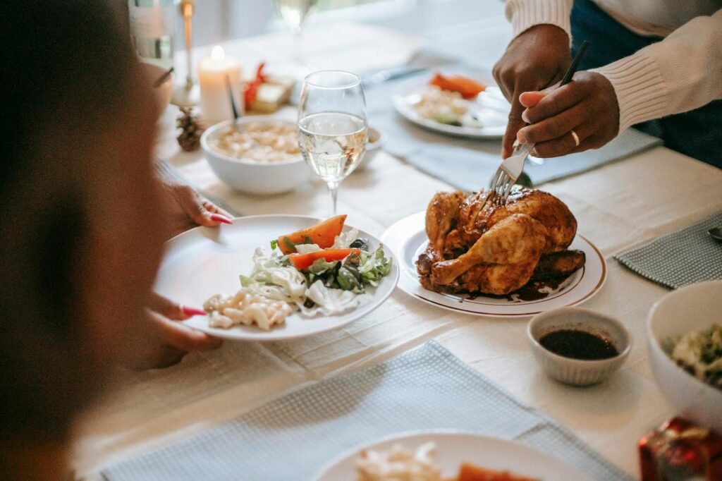 A roast chicken dinner with a gravy boat, cutting board, and simple side dishes on a table.