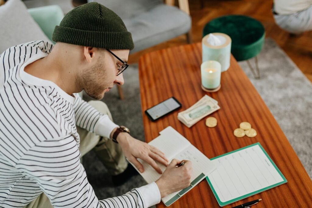 A notebook and grocery list next to leftover containers on a kitchen table