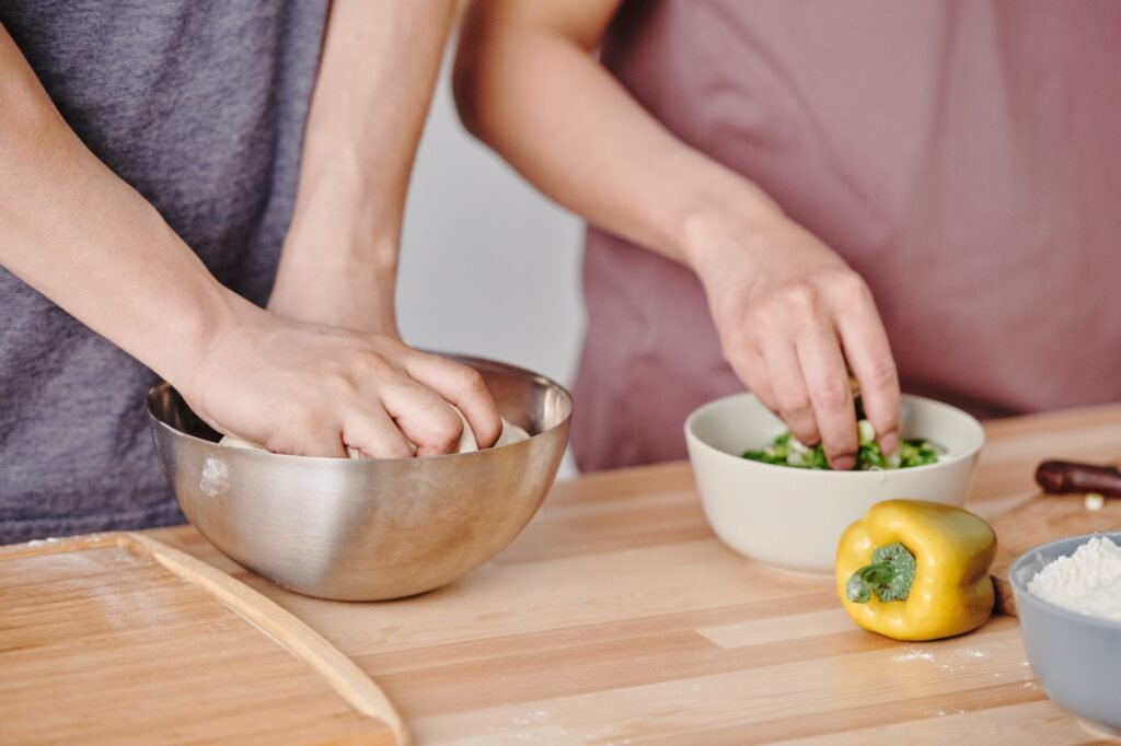 Cut vegetables sorted into bowls beside two sheet pans on a kitchen counter