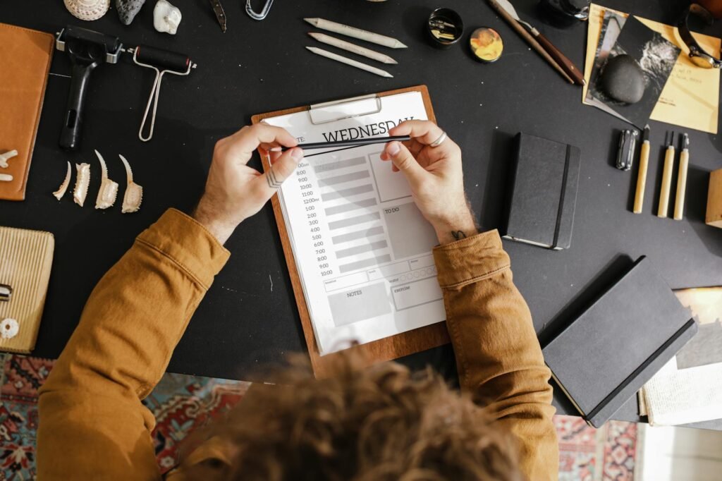A weekly meal-planning notebook beside a grocery list and calculator on a kitchen table.